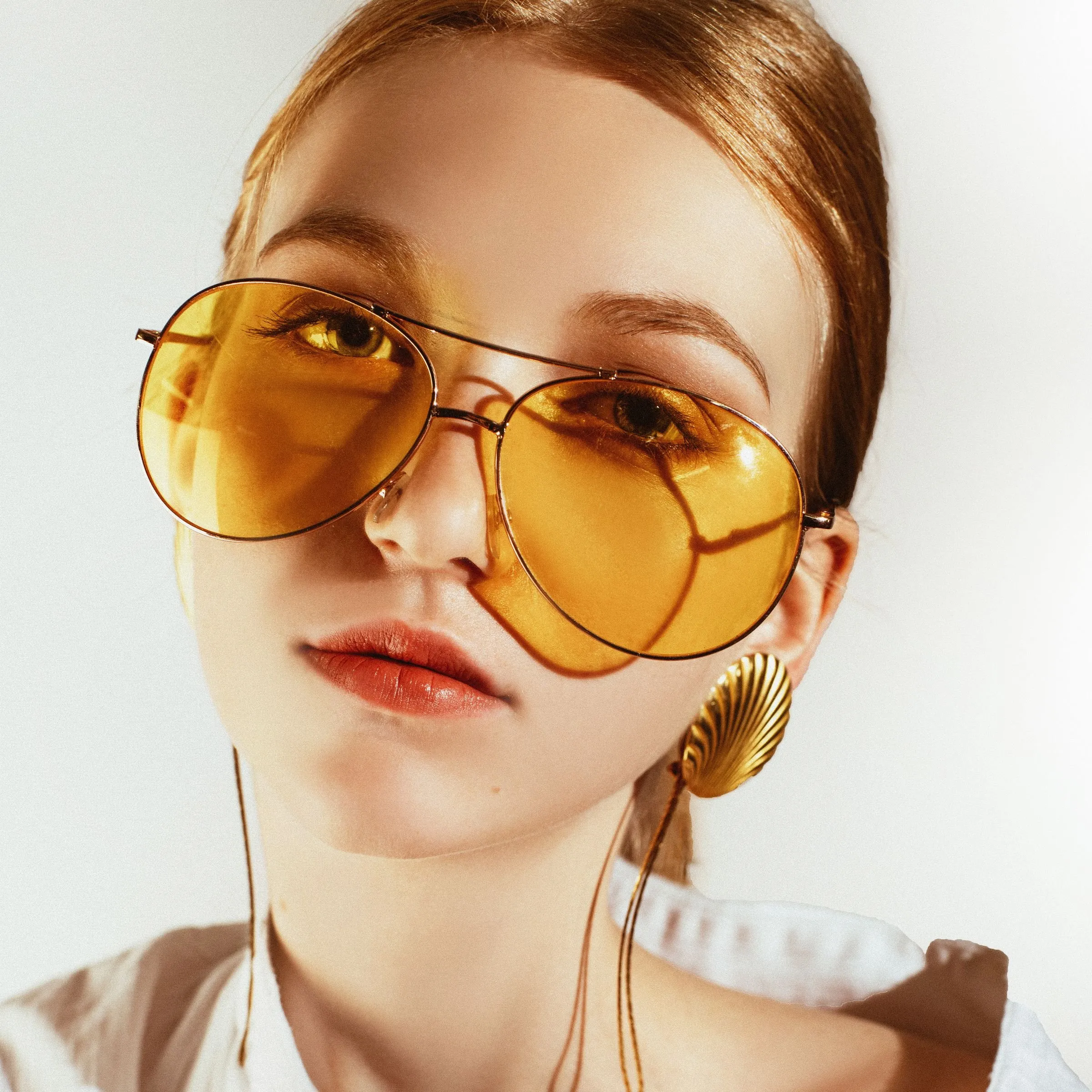 Mujer con gafas de sol tipo aviador de lentes amarillos y montura dorada