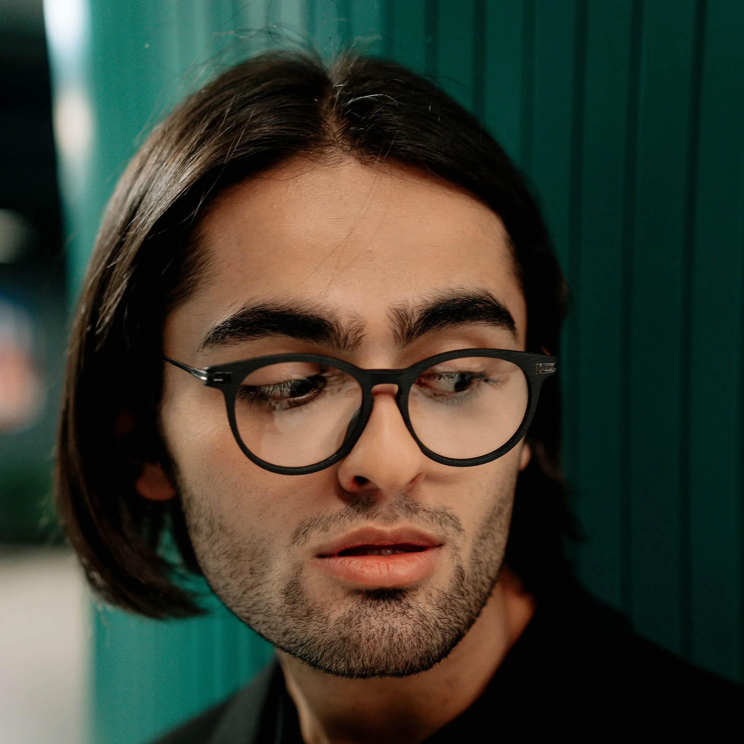 Hombre con gafas redondas de montura negra mirando hacia abajo