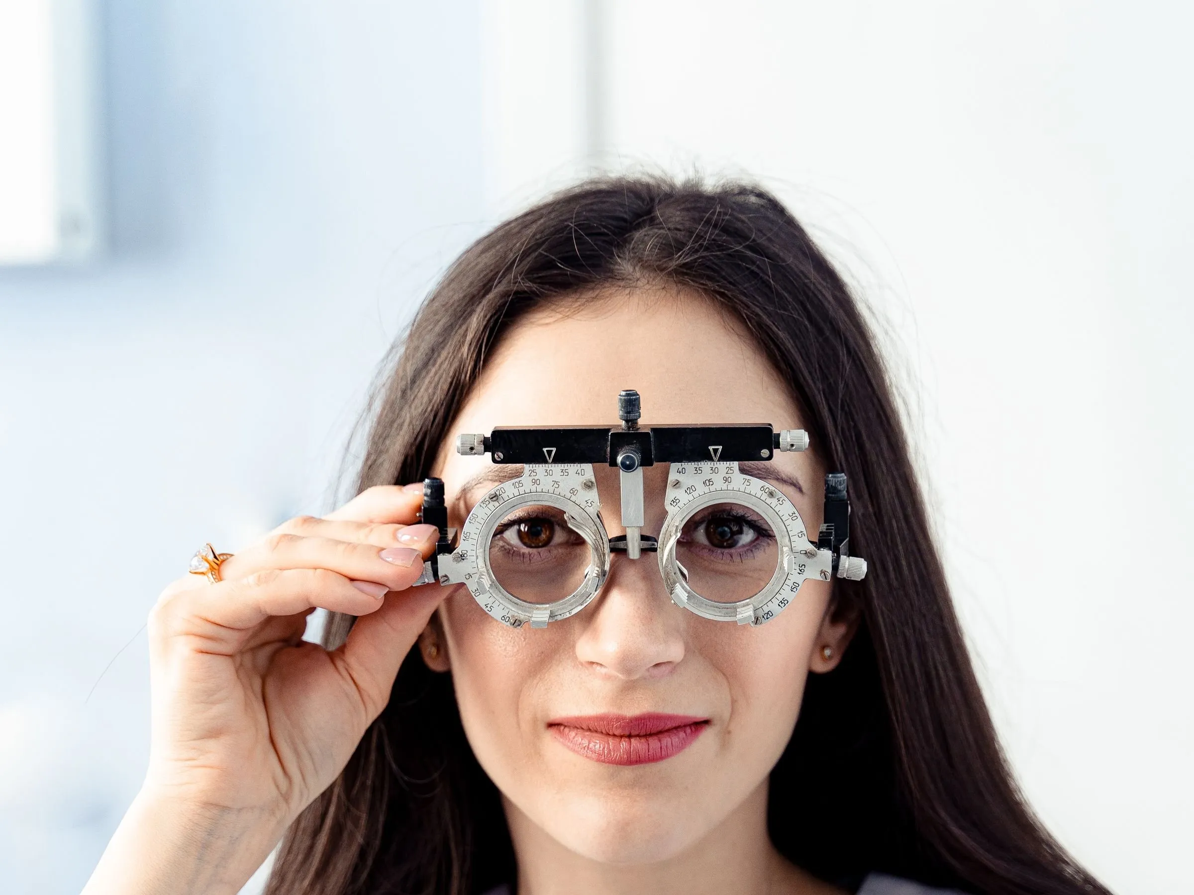 Mujer con un armazón de prueba optométrico frente a los ojos