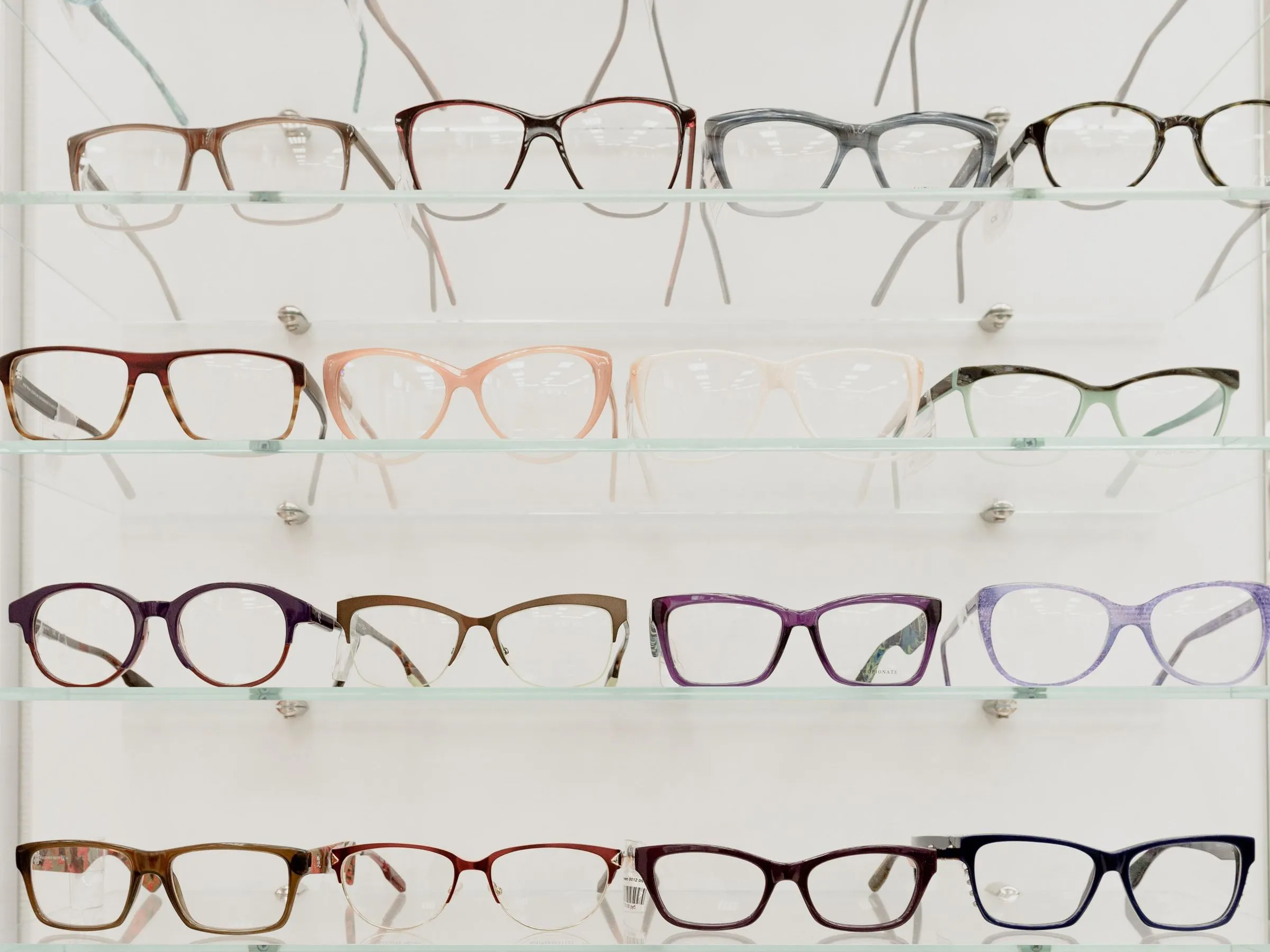 Vitrina con monturas de gafas de distintos colores en estantes de vidrio